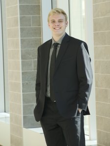 Headshot of Jacob Steiner in a black suit with a grey shirt and a black tie in Sangren Hall