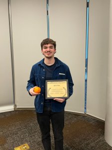 Ralko holds an orange and a certificate for winning a 24-hour film contest.