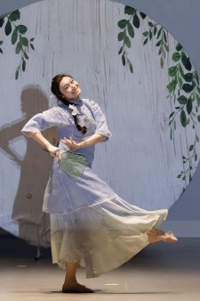 Woman performs Asian cultural dance on stage at Spring Gala.