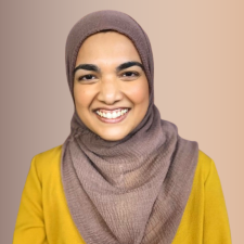 Professional photo of Naaima Khan in a gold top in front of a tan background.