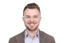 Photo of Nate Mandel in a suit jacket and glasses in front of a white background