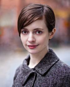Head and shoulders portrait of a young woman with short brown hair wearing a wool coat.