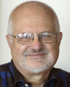 Head and shoulders portrait of an older balding man with glasses.